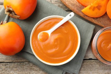 Lezzetli hurma reçeli ve ahşap masada taze meyveler.