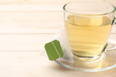 Çay poşeti ve cam bardak açık ahşap masada, yakın plan. Metin için boşluk