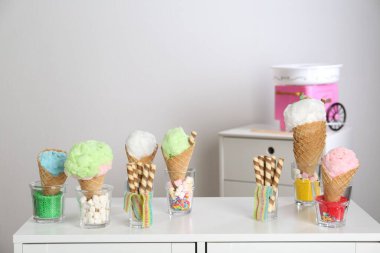 Waffle külahında pamuk şeker ve masadaki diğer tatlılar