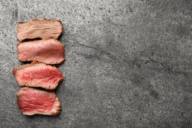 Gri masa üzerinde farklı derecelerde doness ile lezzetli dilimlenmiş sığır filetosu, üst manzara. Metin için boşluk