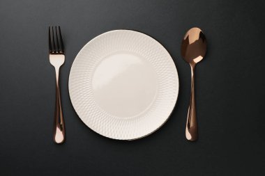 Boş tabak, altın çatal ve kaşık siyah masa, üst manzara