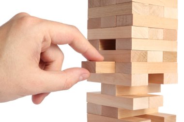 Jenga oynuyorum. Beyaz arkaplandaki tahta bloğu kuleden kaldıran adam, yakın plan