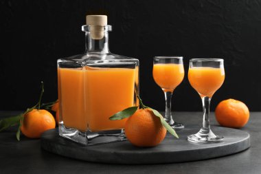 Lezzetli mandalina likörü ve gri masada taze meyveler.