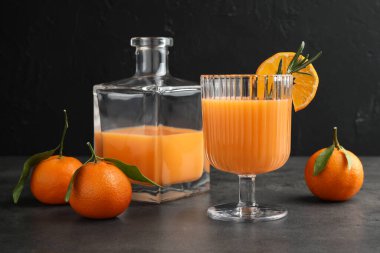 Lezzetli mandalina likörü ve gri masada taze meyveler.