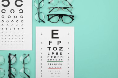 Vizyon testi çizelgesi ve turkuaz arka planda gözlükler düz konumda. Metin için boşluk