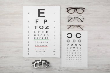 Vizyon testi çizelgesi, gözlük ve deneme çerçevesi açık ahşap arka plan, düz yatış