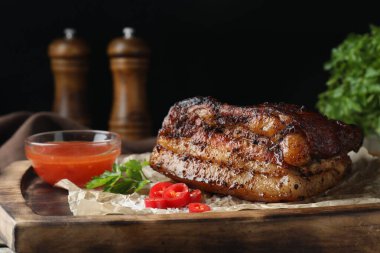 Ahşap tahtada soslu ve kırmızı biberli fırında domuz göbeği servis ediliyor.