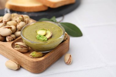 Fıstıklı krema kasede, fındıklı beyaz fayanslı masa, yakın plan. Metin için boşluk