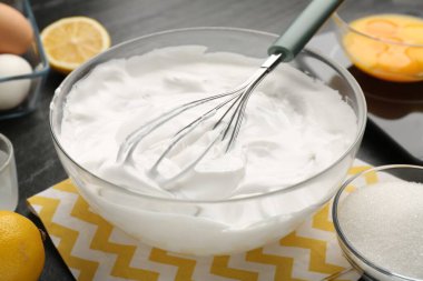 Krem şantili kase, çırpılmış çırpılmış ve malzemeler masada, yakın plan.