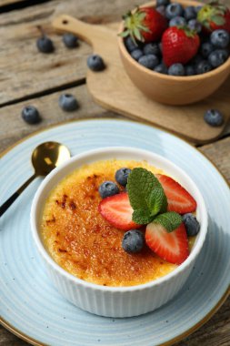 Böğürtlenli ve nane şekerli nefis creme brulee ahşap masada, yakın plan