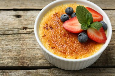 Manzaranın üstünde, ahşap masada, böğürtlenli ve nane şekerli nefis creme brulee. Metin için boşluk