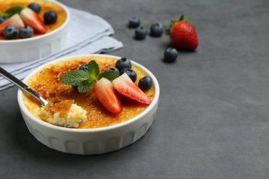 Lezzetli creme brulee kasede böğürtlen ve gri masada kaşık. Metin için boşluk