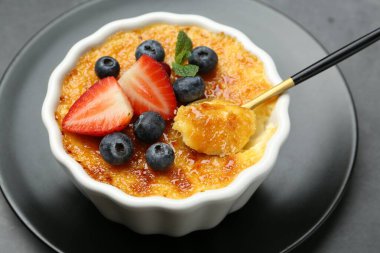 Gri masadaki kaseden meyveli ve nane şekerli nefis creme brulee alıyorum.