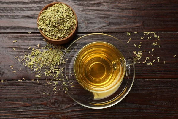 Aromatic fennel tea and seeds on wooden table, flat lay
