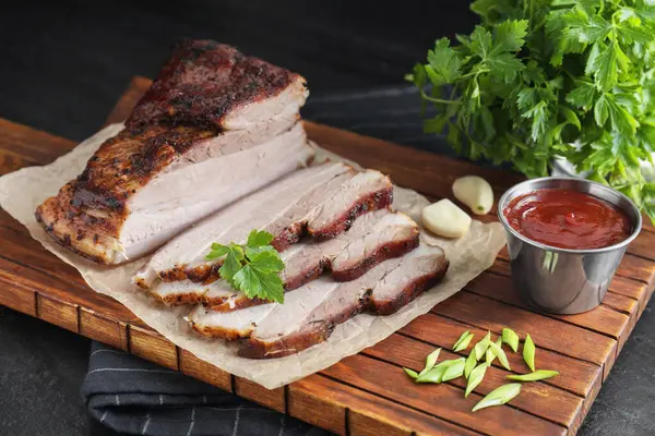 Kurutulmuş domuz eti parçaları soslu ve maydanozlu siyah desenli masa, yakın plan.