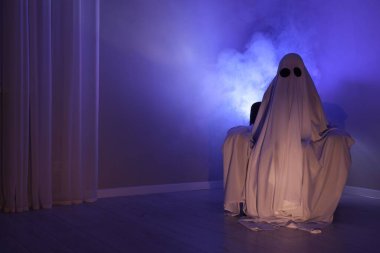 Ürkütücü hayalet. Mavi ışıkta koltukta oturan çarşaflı kadın, metin için boşluk.