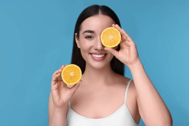 Açık mavi arka planda turuncu parçaları olan güzel genç bir kadın.