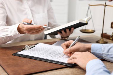 Ofisteki ahşap masada evraklarla çalışan avukatlar, yakın plan.