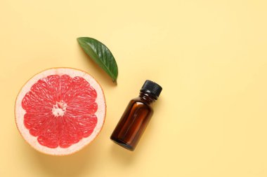 İçinde greyfurt yağı, yaprak ve soluk sarı arka planda taze meyve bulunan bir şişe. Metin için boşluk