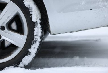 Car with winter tires on snowy road, closeup clipart