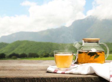 Cam bardakta yeşil çay ve dağlarda ahşap masa üzerinde çaydanlık, metin için yer
