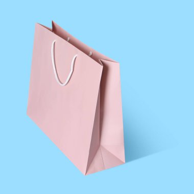 Açık mavi arka planda havada pembe alışveriş torbası