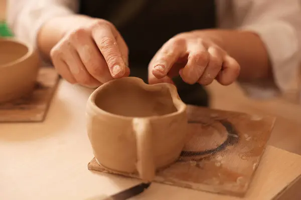Pottery crafting. Woman sculpting with clay at table, closeup