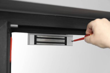 Tornavidalı bir adam elektromanyetik kapı kilidi yerleştiriyor, yakın plan. Ev güvenliği