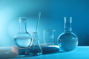 Laboratuvar analizi. Masada açık mavi arkaplana karşı farklı cam eşyalar