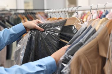 Kuru temizleme servisi. Kadın plastik torba içinde ceketini alıyor, kapalı mekandan, yakın plan.