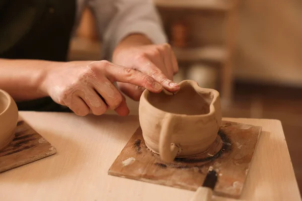 Pottery crafting. Woman sculpting with clay at table indoors, closeup