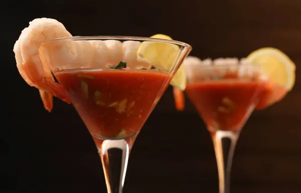 Tasty shrimp cocktail with sauce in glasses on dark background, closeup
