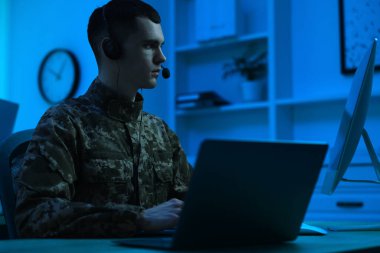 Askerlik. Kulaklıklı asker geceleri ofiste çalışıyor.