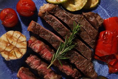 Lezzetli ızgara biftek, sebze ve baharat tabakta.