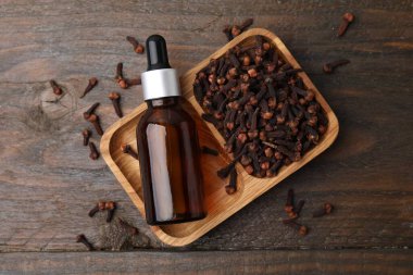 Şişedeki karanfil yağı ve ahşap masada kurumuş tomurcuklar.