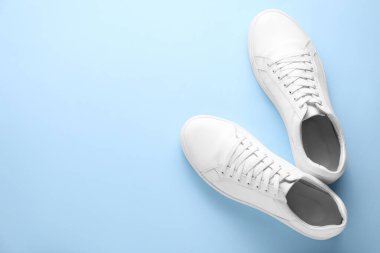 Açık mavi arka planda bir çift şık beyaz spor ayakkabı, üst manzara. Metin için boşluk