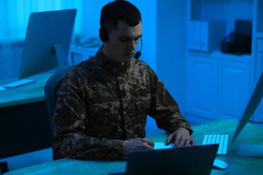 Askerlik. Kulaklıklı asker geceleri ofiste ahşap masada çalışıyor.