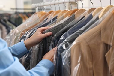 Kuru temizleme servisi. Kadın plastik torba içinde ceketini alıyor, kapalı mekandan, yakın plan.