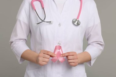 Gri arka planda pembe kurdeleli Mammolog, yakın plan. Göğüs kanseri farkındalığı