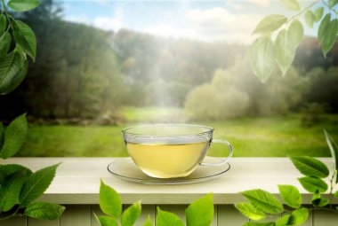 Dağlarda açık ahşap masada cam fincanda yeşil çay