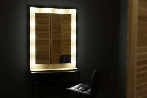 Beautiful mirror with light bulbs and chair in makeup room