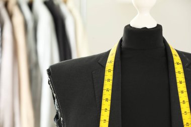 Tamamlanmamış ceketli manken ve terzi dükkanında mezura, yakın plan. Metin için boşluk