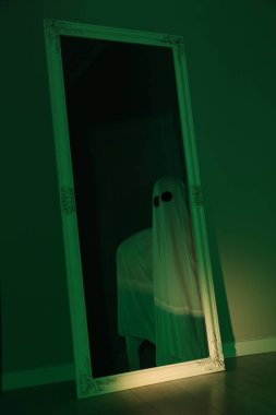 Ürkütücü hayalet. Yeşil ışıkla kaplanmış kadın, aynadaki yansıma.