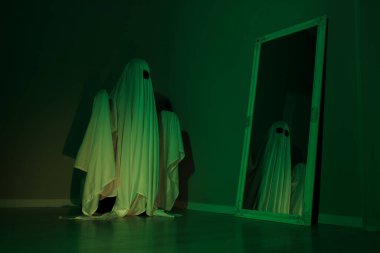 Ürkütücü hayalet. Yeşil ışıkta aynaya bakan çarşaflı kadın.