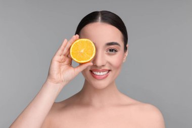 Gri arkaplanı turuncu olan güzel bir genç kadın.