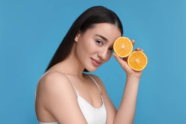 Açık mavi arka planda turuncu parçaları olan güzel genç bir kadın.