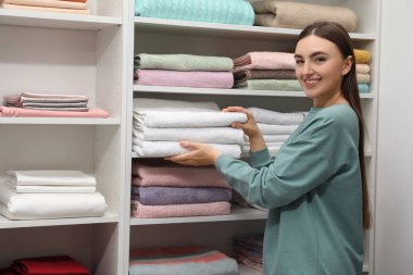 Mutlu müşteri çarşaf dükkanında havlu seçiyor, mesaj için yer var.