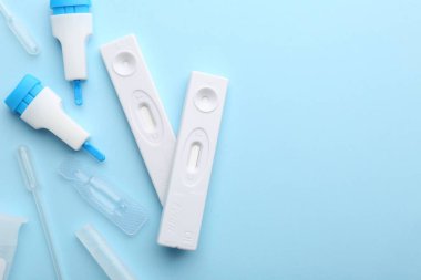 Açık mavi arkaplanda tek kullanımlık test kitleri, düz konum. Metin için boşluk