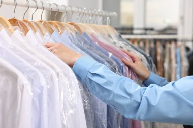 Kuru temizleme servisi. Kadın gömleğini plastik torbaya koyuyor, kapalı mekandan, yakın plan.