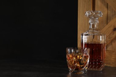 Siyah arka planda, sehpanın üzerindeki tahta sandığın yanında cam ve şişe içinde viski. Metin için boşluk